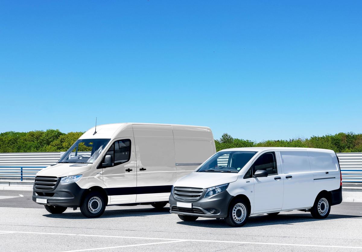 Twee witte bestelwagens op een parking onder een blauwe lucht